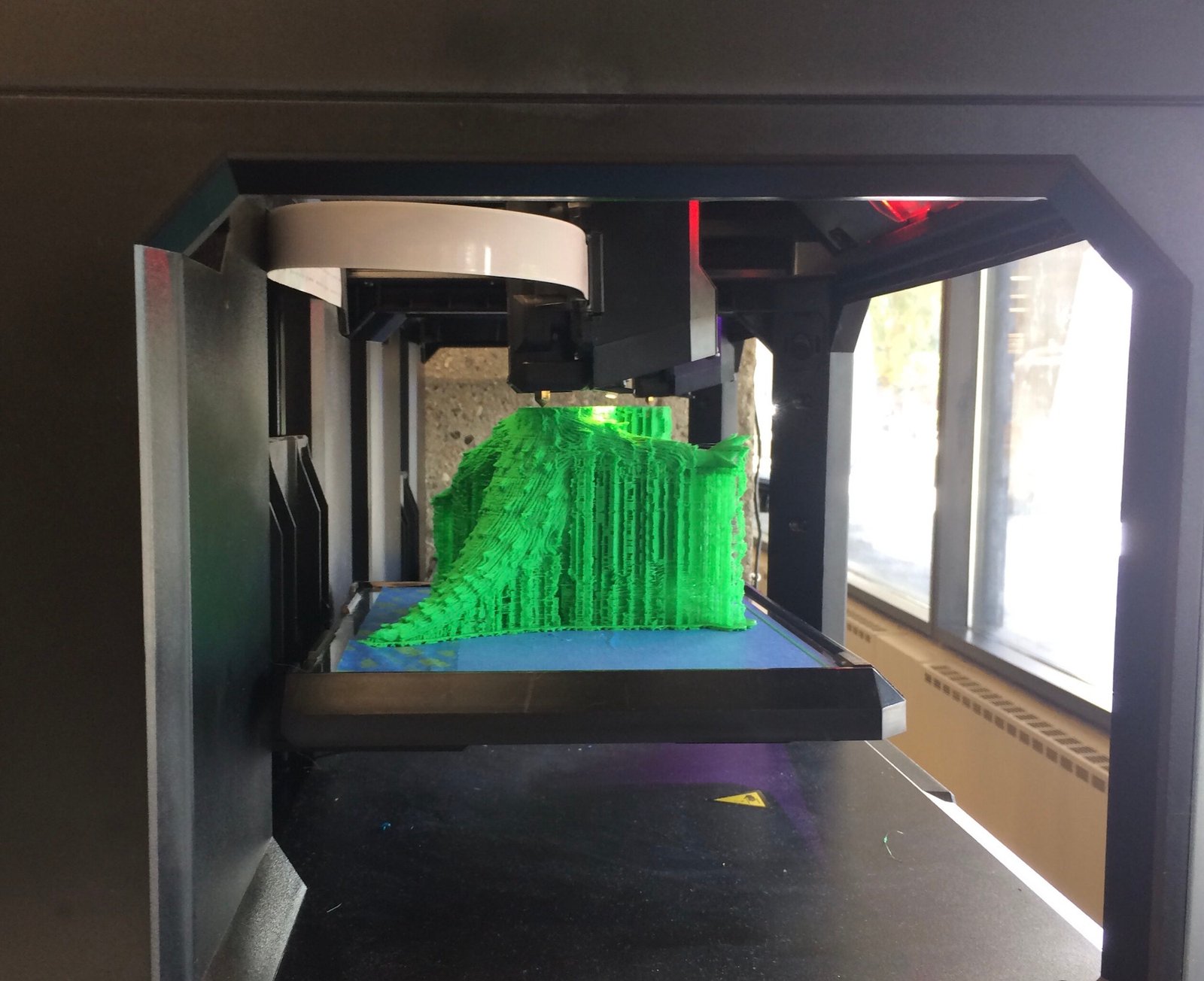 3D printer printing a three-dimensional green model for a class project with futuristic technology